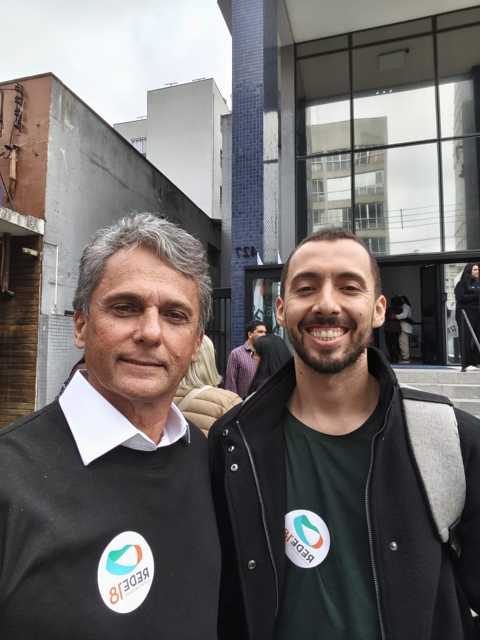 Agnaldo Baraldi ao lado de um apoiador, os dois com o adesivo do número 18